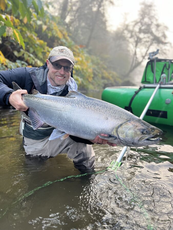 Angler in the river holding a king salmon