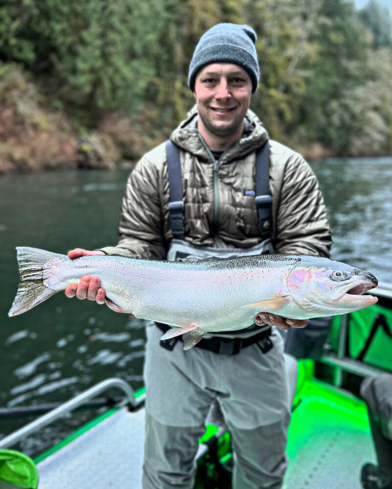 Angler in a beanie holding a bright winter steelhead