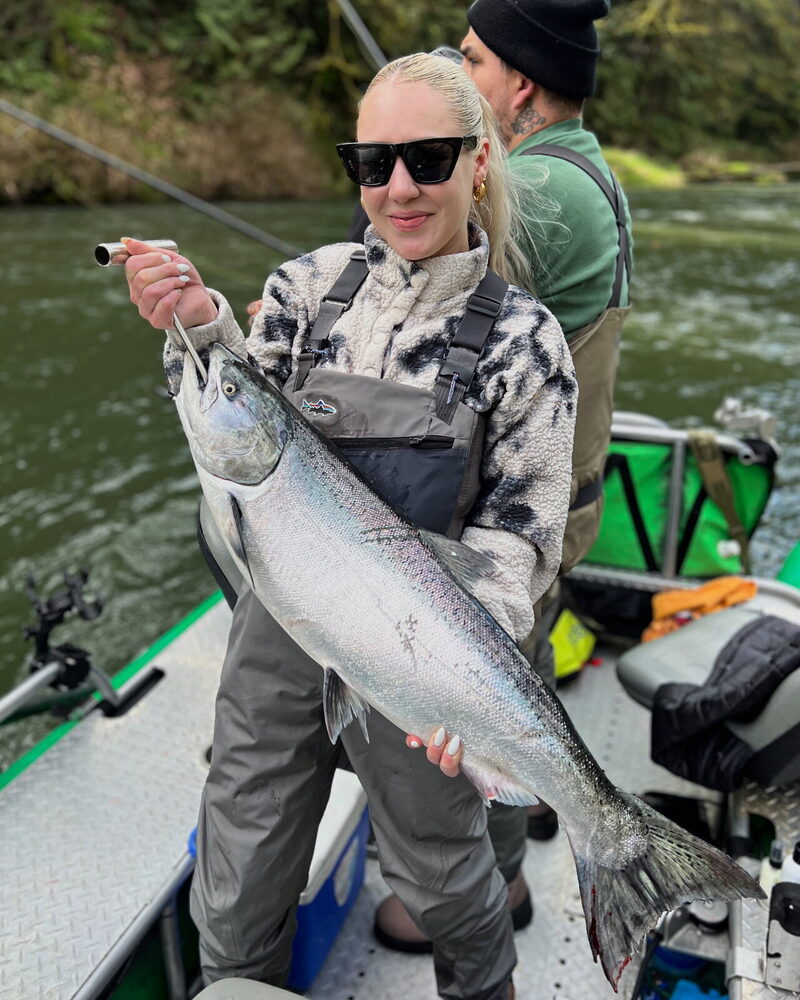Angler holding a chrome steelhead on the bank at last light