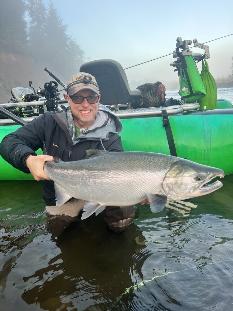 Angler kneeling in the shallows with a big hook-jawed buck