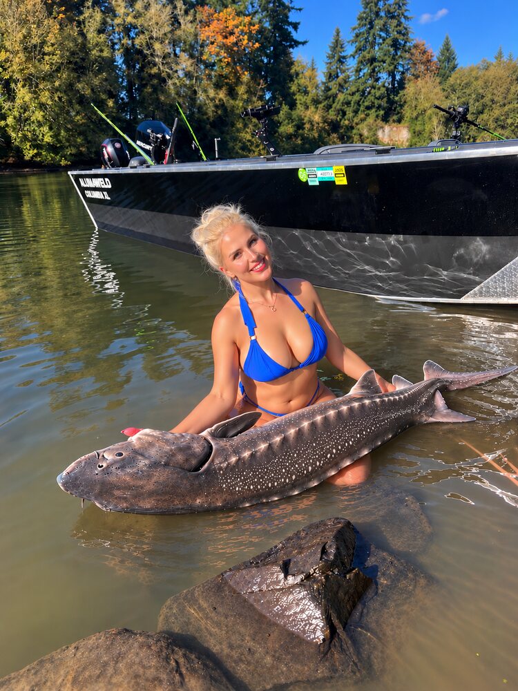 Angler in the shallows beside the jet sled holding a white sturgeon