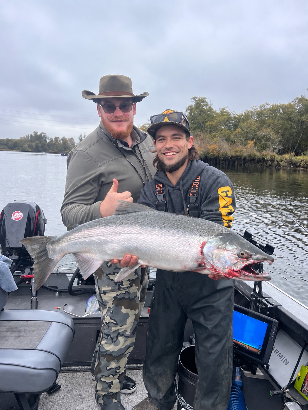 Captain Josh Miller with a client and a fresh salmon aboard the boat